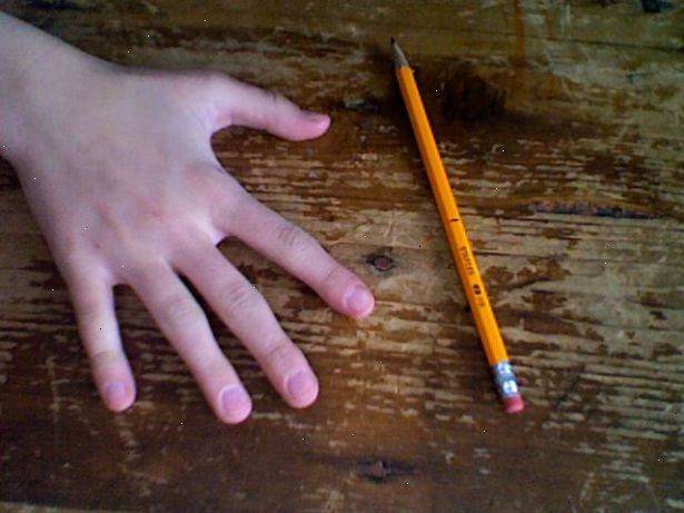 Hur att snurra en penna runt långfingret. Håll pennan som du skulle när du skriver, förutom placera den mellan mitten och ringfingret, greppa den på mitten.