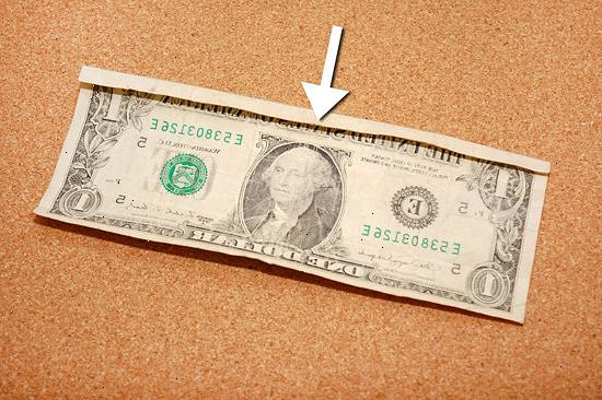 Hur man viker en dollarsedel att göra ett finger ring. Placera räkningen på en plan yta, uppåt.